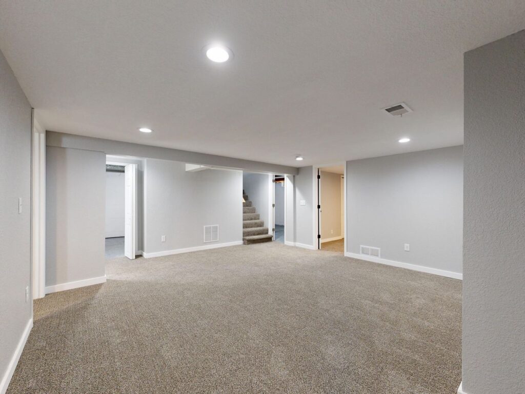 Home Spacious modern basement with neutral design and carpet flooring, perfect for renovation or real estate listings.